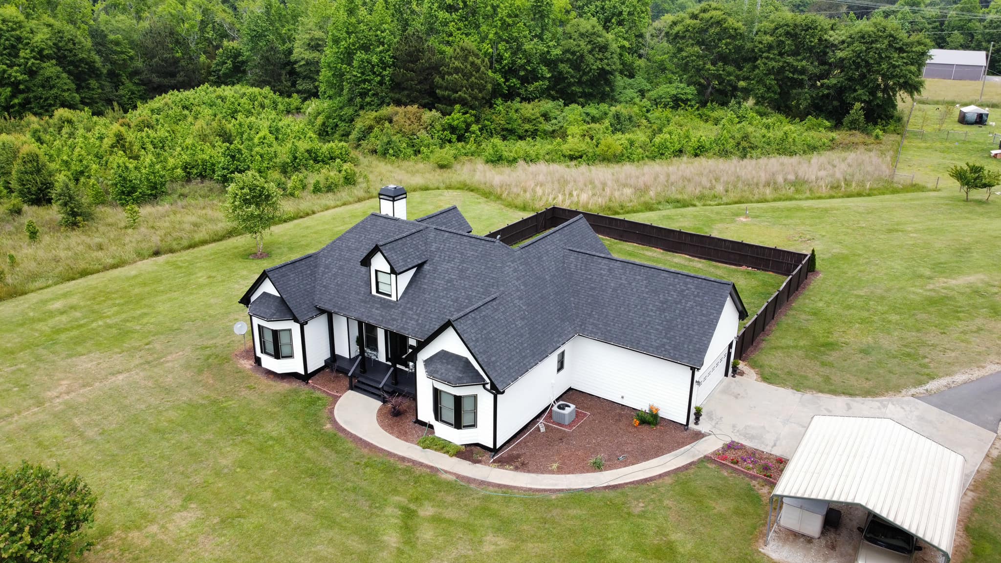 Aerial view of a white farmhouse with a new charcoal shingle roof
